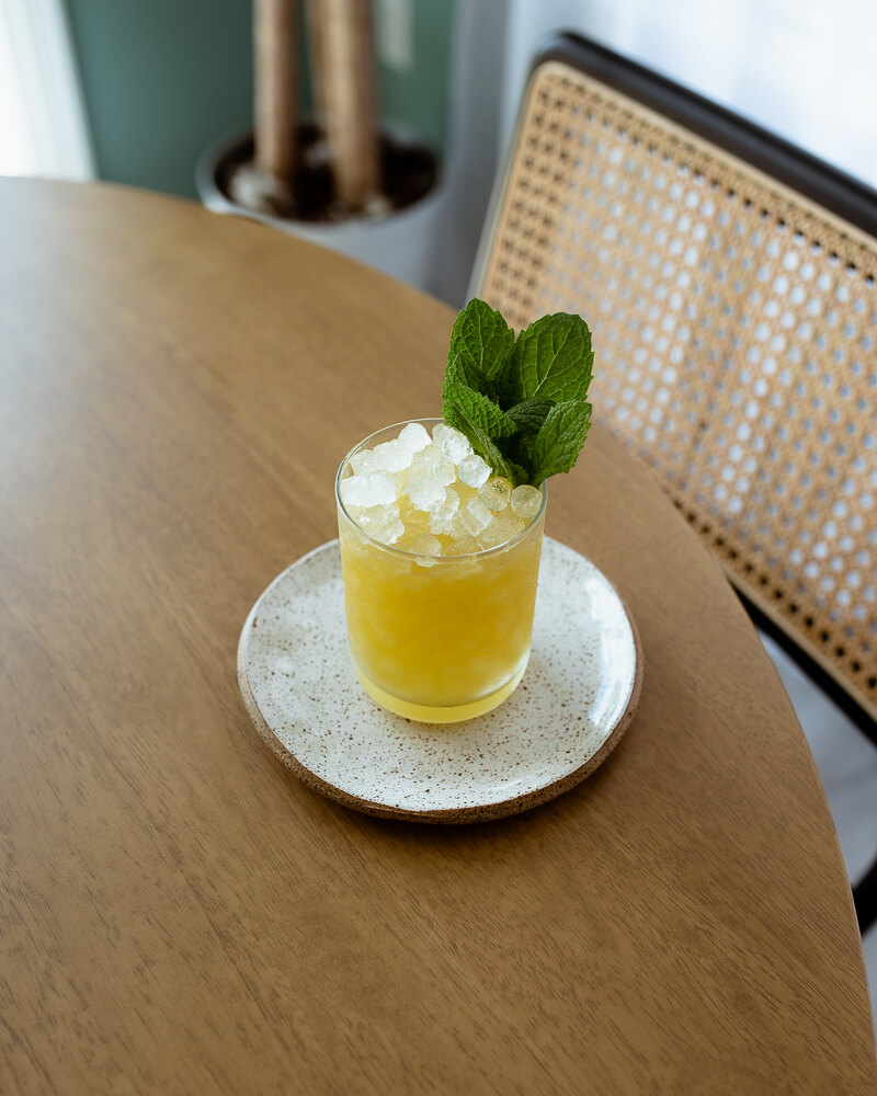 Petty Crime Cocktail with fernet, banana and Jamaican rum, garnished with mint over pebble ice
